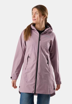 Femme portant un long imperméable mauve à capuche avec une fermeture éclair et des poches noires, debout et regardant sur le côté.