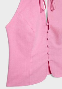 Veste sans manches en lin rose avec des boutons recouverts de tissu sur le devant et une fermeture à nouer au niveau de l'encolure.