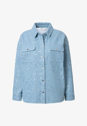 Camisa de mezclilla azul clara con lentejuelas plateadas, mangas largas, cuello, dos bolsillos en el pecho y cierre de botones a presión. Textura suave y adornos detallados.
