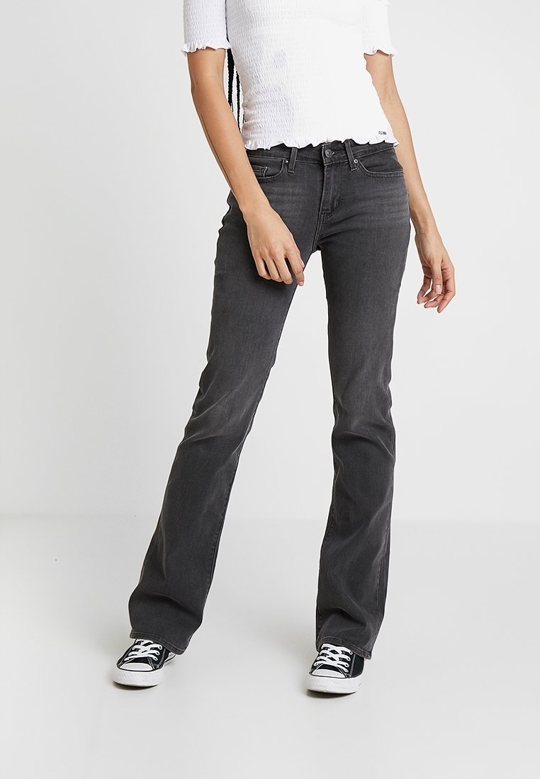 Sorte vide jeans i blødt denimstof med midtalje, fem-lomme-design og bæltestropper, stylet med sorte sneakers.