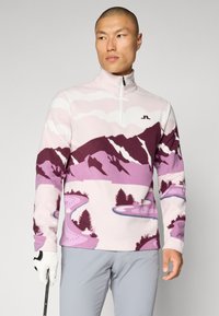 Pullover in fleece di un rosa chiaro con motivo di montagne e fiumi in tonalità di viola. Presenta una zip a un quarto e un logo ricamato sul petto.