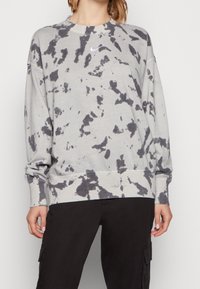Sudadera tie-dye gris hecha de tela suave, con cuello redondo y mangas largas con puños acanalados. Pequeño logo de Nike en el pecho.