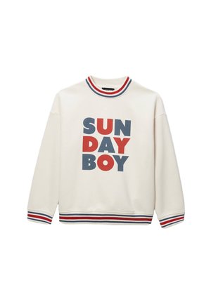 Sweatshirt crème avec "SUNDAY BOY" imprimé en lettres rouges et bleues en gras. Il possède un col côtelé et des poignets rayés en rouge, blanc et bleu.