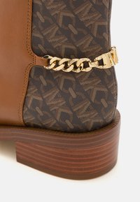 Brown leather and dark patterned textile ankle boot with a gold chain accent and a stacked wooden heel. Textured surface and contrast stitching.