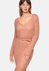 Rosa Strickkleid mit rundem Ausschnitt, langen Ärmeln und figurbetonter Silhouette, akzentuiert durch einen passenden Ledergürtel. Durchgehend strukturiertes Muster.