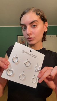 Šešios sidabrinės mėnulio formos auskarų poros išdėstytos ant baltos kortelės. Dizainai apima lygius, tekstūruotus ir sukti stilius, turinčius skirtingus skersmenis.