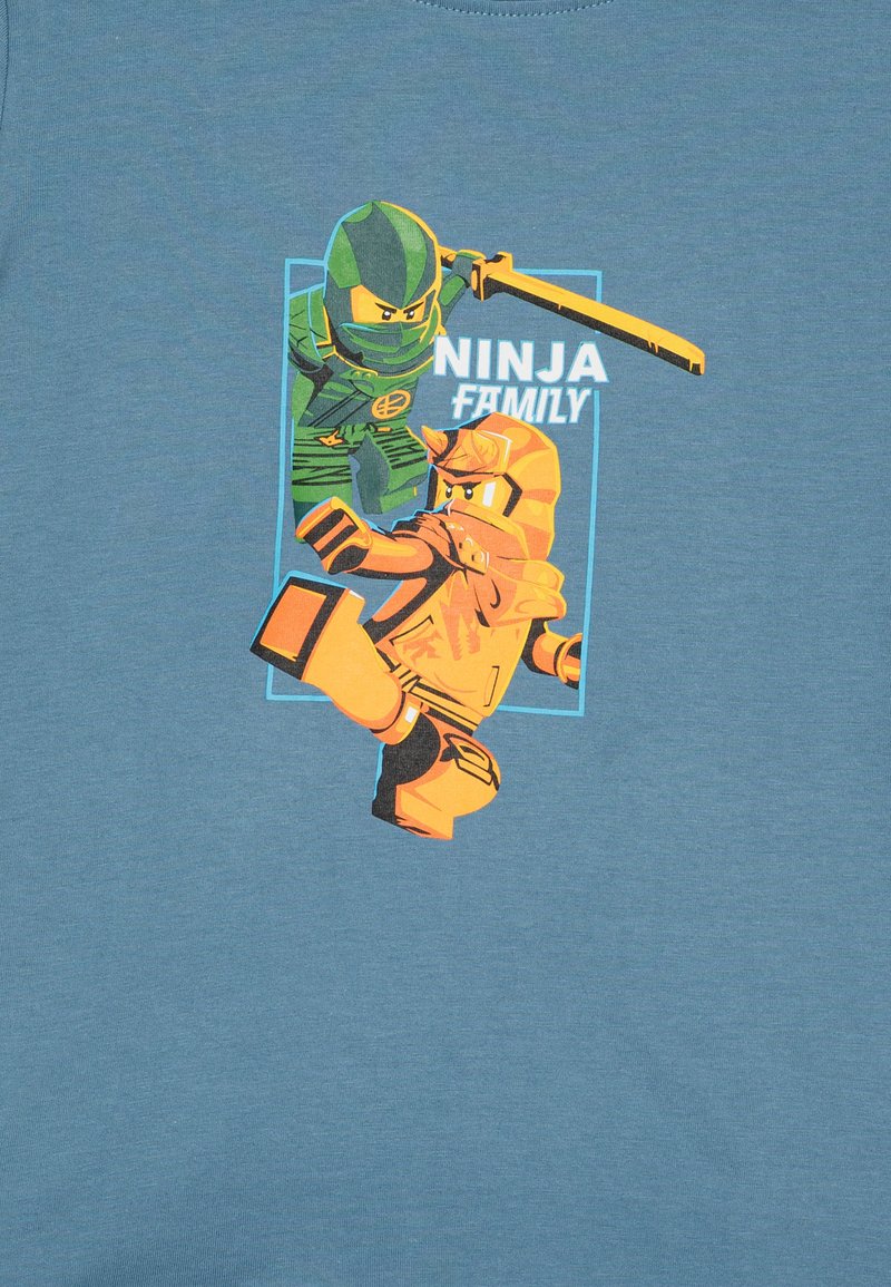 Navyblaue T-Shirt mit einem Grafik von zwei Ninjas: einer in Grün mit einem Schwert, der andere in Orange, der einen Kick ausführt. Der Text lautet "NINJA-FAMILIE".