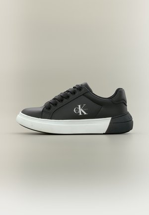 Μαύρο sneaker χαμηλού προφίλ με λευκή σόλα, μαύρα κορδόνια και το λογότυπο Calvin Klein στο πλάι.