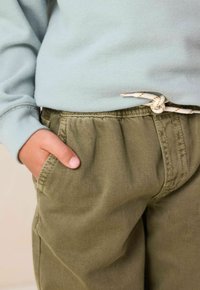 Muntgroene sweatshirt met ribgebreide manchetten, gecombineerd met olijfgroene broek met een elastische tailleband en een knoopdrawstring.