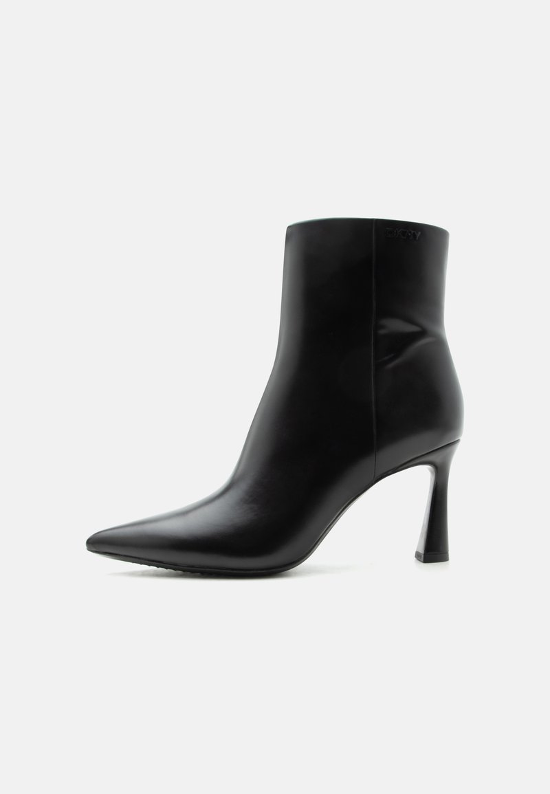 Bottine en cuir noir avec bout pointu et talon aiguille fin et haut, vue de profil sur fond blanc.