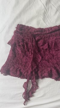 Burgundská krajková sukně s volánkovým lemem a zavazováním, zdobená složitými květinovými vzory a jemnou, měkkou texturou.