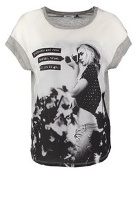 Kortærmet t-shirt med en grå og hvid farvepalet, med et grafisk print af en person, tekstoverlag og prikmønstre.