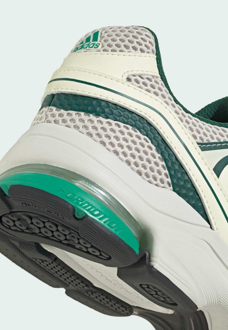 Sneaker mit einem grauen Mesh-Obermaterial, grünen Akzenten und einer weißen Sohle. Verfügt über eine sichtbare Luftkammer und strukturierte Muster auf der Sohle.