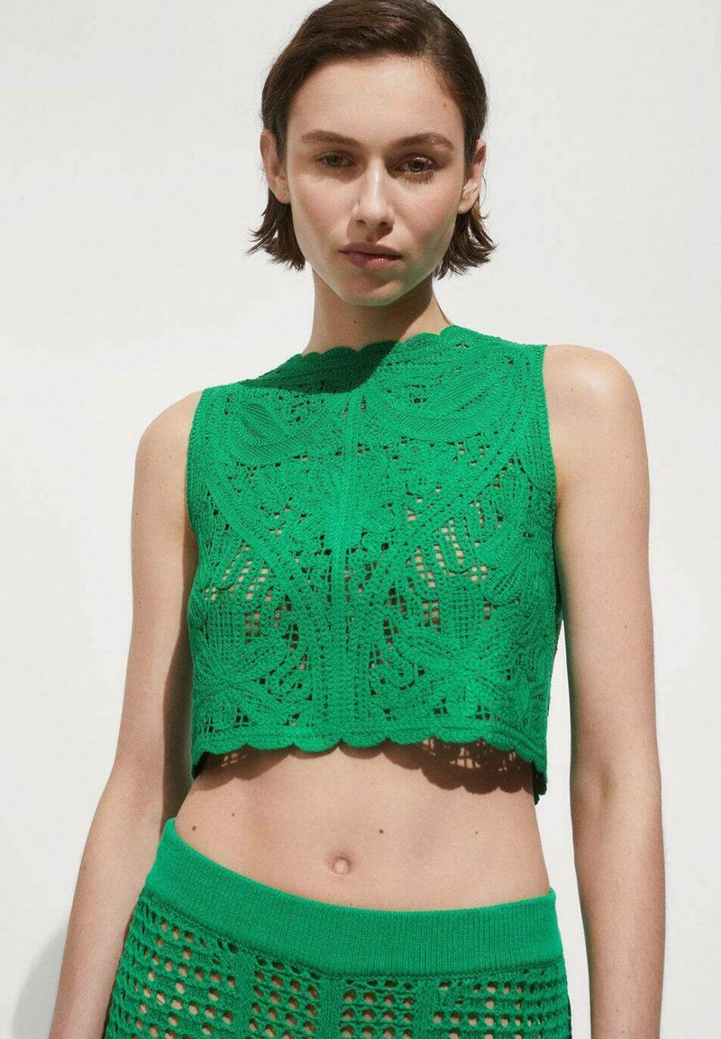 Grüner gestrickter Crop-Top mit kunstvollen Spitzenmustern und gewelltem Ausschnitt, ergänzt durch einen passenden, hoch taillierten Strickrock.