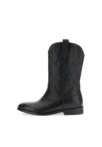 Bota vaquera de cuero negro con costuras decorativas elevadas, puntera puntiaguda y una pestaña en la parte trasera. Diseño elegante con suela plana y un acabado ligeramente brillante.