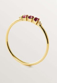 Anillo de oro con tres gemas redondas de color rosa intenso engastadas en un diseño de garras, con una pequeña piedra clara que acentúa la banda.