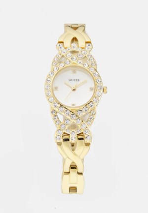 Montre-bracelet Guess dorée avec des accents en cristal sur la lunette et le bracelet, cadran blanc, et aiguilles des heures, minutes et secondes en or.