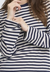 Pikamuhuline särk meresiniste ja kreemjate horisontaaltriipudega, ümar kaelusega ja lahtiste varrukatega. Pehme puuvillasegu materjal.