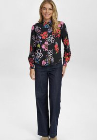 Blusa nera a fiori con stampa multicolore vivace, maniche lunghe e colletto a camicia abbinata a pantaloni a gamba larga in denim scuro.