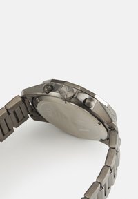 Μεταλλικό ρολόι με ματ σκούρο γκρι φινίρισμα, με στρογγυλή κάσα, δύο πλήκτρα και βραχιόλι τύπου σύνδεσης. Καπέλο επίπεδο με χαραγμένα σημάδια.