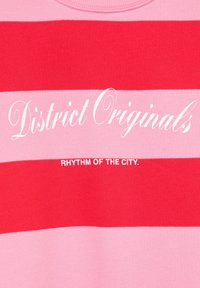 Tissu rayé rouge et rose avec un texte blanc indiquant « "District Originals" » et un texte plus petit en dessous disant « "Rhythm of the City." »