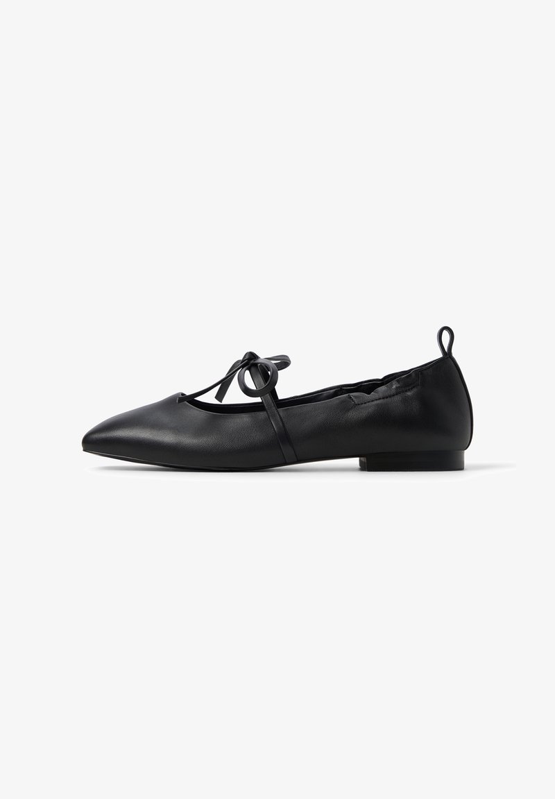 Ballerine en cuir noir avec bout pointu, petit talon, bride latérale et fermeture par nœud.