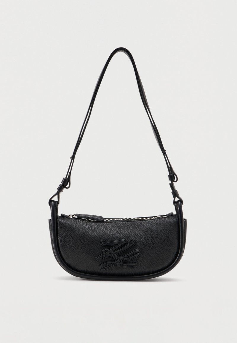 Μαύρη δερμάτινη τσάντα ώμου με καμπύλο σχήμα, υφή στην επιφάνεια, κλείσιμο με φερμουάρ και ανάγλυφο διακοσμητικό λογότυπο στο μπροστινό μέρος.