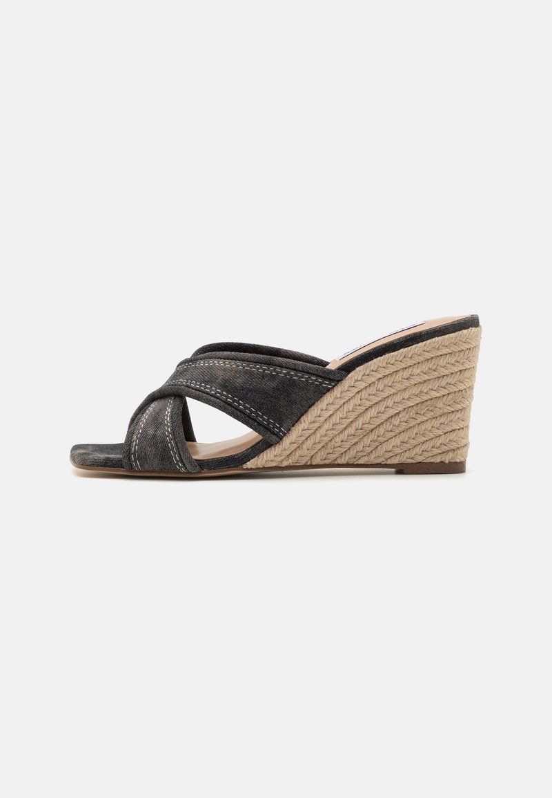 Les sandales à talons compensés noires présentent un dessus en tissu texturé avec des brides entrecroisées et une semelle en jute tressé, mettant en valeur un compartiment pour le pied lisse.