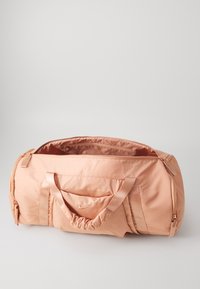 Roze nylon sporttas met dubbele handgrepen, rits sluiting, voorvak en geplooide designelementen. Gladde textuur, lichtgewicht constructie.