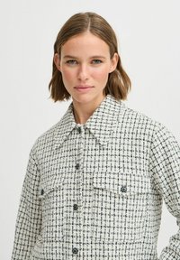 Hvid og marineblå ternet jakke, vævet tekstur, klassisk krave, knaplukning foran, to brystlommer, let oversized pasform.