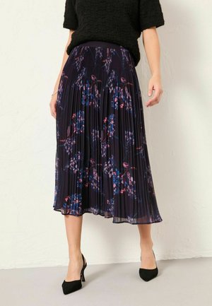 Faltenrock in Midi-Länge aus dunklem Stoff mit floralem Muster in Blau und Rosa. Verfügt über einen elastischen Bund und fällt unter das Knie. Schwarze High Heels.
