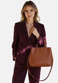Borsa a spalla in pelle marrone con texture a granuli, dotata di manici corti e di una tracolla rimovibile. Logo stampato sul davanti.