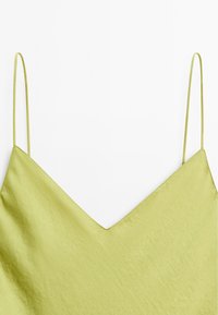 Satin-Camisole in hellem olivgrün mit verstellbaren dünnen Trägern und V-Ausschnitt, zeichnet sich durch eine glatte Textur und klare Linien aus.