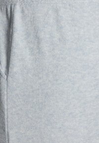 Gaiši zili sporta bikses, izgatavotas no mīksta auduma, ar strukturētu virsmu un sānu kabatām, kā arī elastīgu jostasvietu ērtībai.