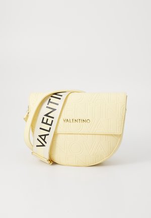 Jasnożółta torebka na ramię Valentino z tłoczonym wzorem logo i szerokim białym paskiem z wyraźnym czarnym napisem "Valentino".