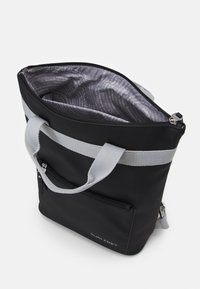 Sac fourre-tout noir avec des poignées en tissu gris, fermeture à glissière et doublure intérieure comportant un texte imprimé. L'extérieur comprend une poche zippée.