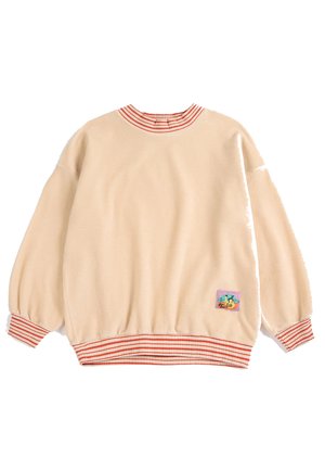 Beige langærmet sweatshirt med rød- og hvidstribet krave, manchetter og kant, med et farverigt tegneseriepatch nær den nederste kant.