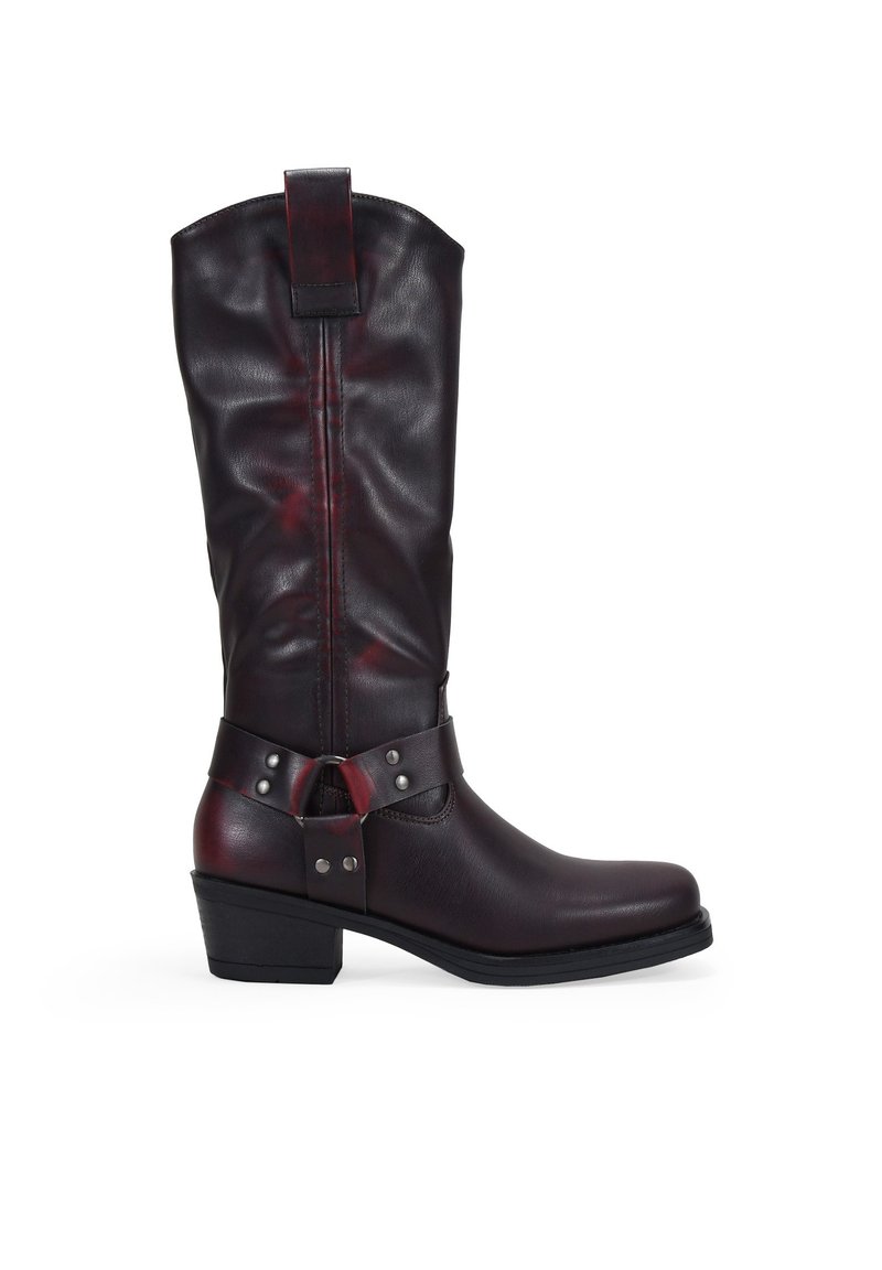 Botas de cuero hasta la rodilla en burdeos oscuro, con un caño ancho, tira en el tobillo con tachuelas plateadas y un tacón ligeramente elevado.