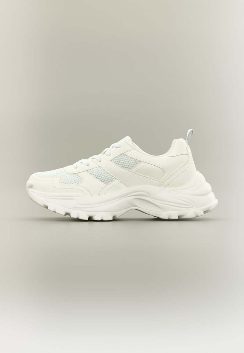 Des baskets blanches de sport avec une tige en mesh texturé, des superpositions synthétiques, un col rembourré et une semelle en caoutchouc épaisse avec un motif de bande de roulement.