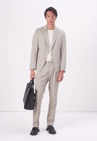 Light grey suit with a slim fit, smooth texture, single-breasted jacket, matching trousers, white shirt, and black bag. Black shoes.