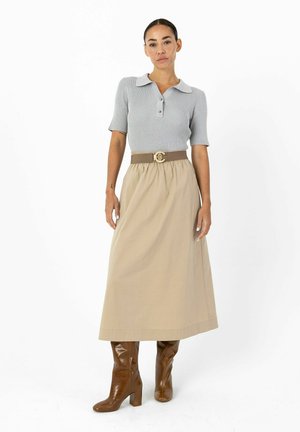 Grå ribstrikket polo med korte ærmer og krave, kombineret med en beige højtaljet nederdel og brune knælange støvler. Bælte med logo-accent.