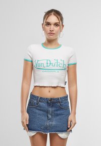 T-shirt blanc à manches courtes avec bordure turquoise et graphique "Von Dutch Originals". Porté avec une mini-jupe en denim avec des bords effilochés.