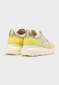 Zapatillas verde lima con acentos metálicos dorados, parte superior de malla texturizada y cuello acolchado; cuentan con una suela blanca gruesa con patrones de tracción.