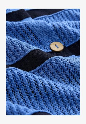 Blau gestrickter Stoff mit einer Spitzenstruktur, gestreiftem Muster mit dunklen Akzenten und einem Holzknotendetail.