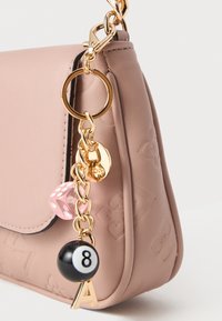 Roze neplederen handtas met een gouden kettingband, voorzien van een hanger met een roze dobbelsteen, een zwarte biljartbal en de gouden letter 'A'.