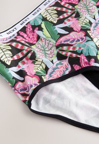 Bas de bikini multicolore avec un motif de feuilles tropicales en rose, vert et blanc sur un fond noir, avec une ceinture élastique noire.