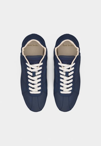 Ζευγάρι μοβ σκούρων δερμάτινων αθλητικών παπουτσιών με λευκά κορδόνια, στρογγυλεμένες μύτες και μπεζ εσωτερική επένδυση, φαίνεται από πάνω πάνω σε λευκό φόντο.