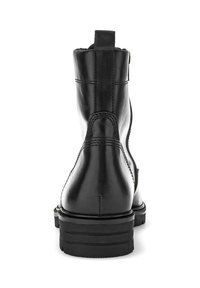 Bottes de cheville en cuir noir avec une finition lisse, bout rond et semelle empilée. Présente une languette et un couturage contrasté sur les côtés.