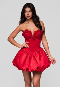 Röd satin klänning med en djup V-ringning prydd med ros-applikationer, en figurnära bodice och en voluminös, rynkad kjol nedanför.