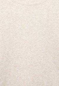 Krém színű kötött anyag közeli felvétele, puha, bolyhos textúrával.